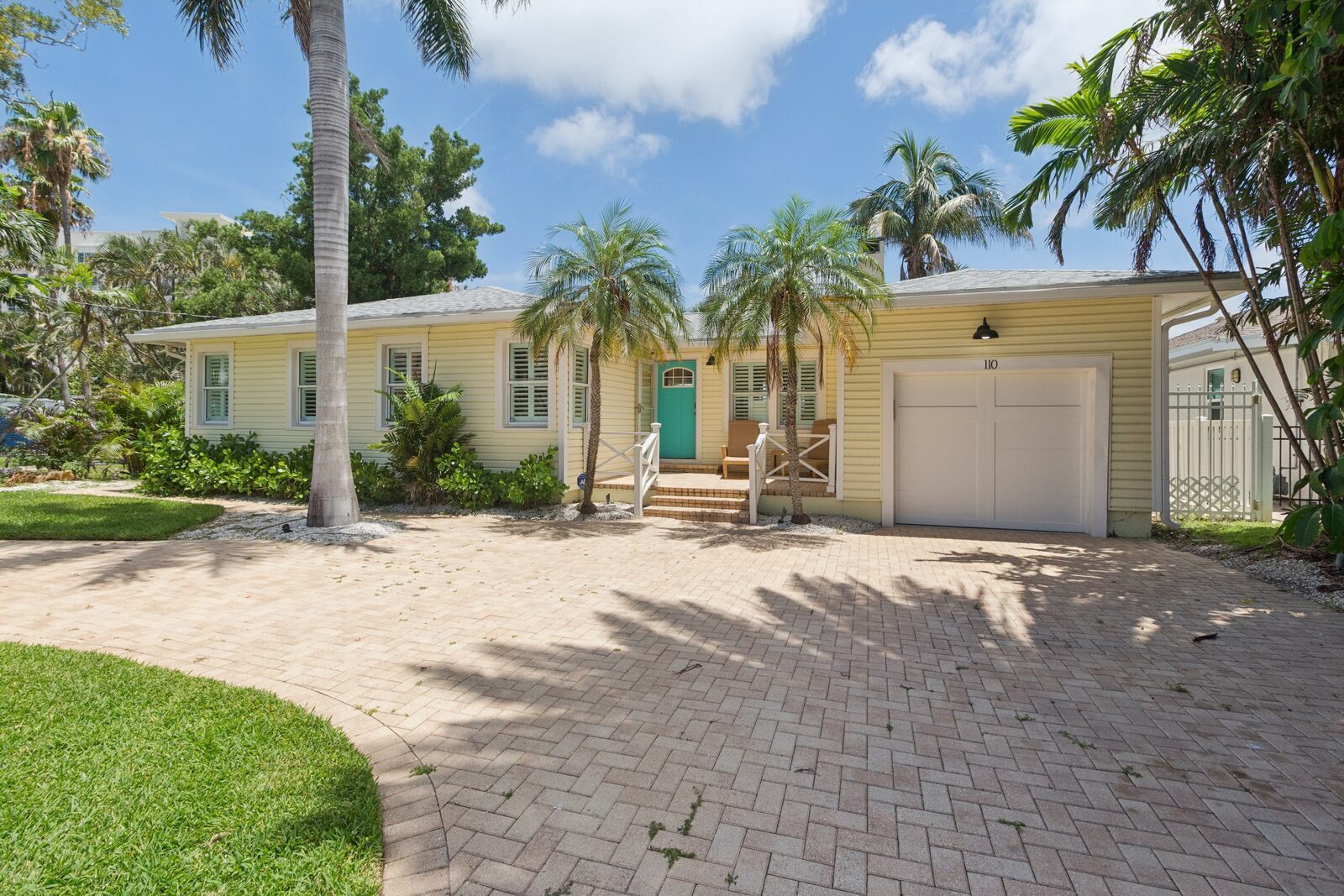Cottage exterior — teal door, palm trees, garage