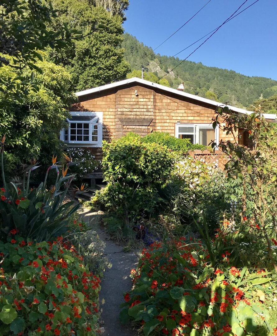 Cottage exterior with garden path and mountain backdrop