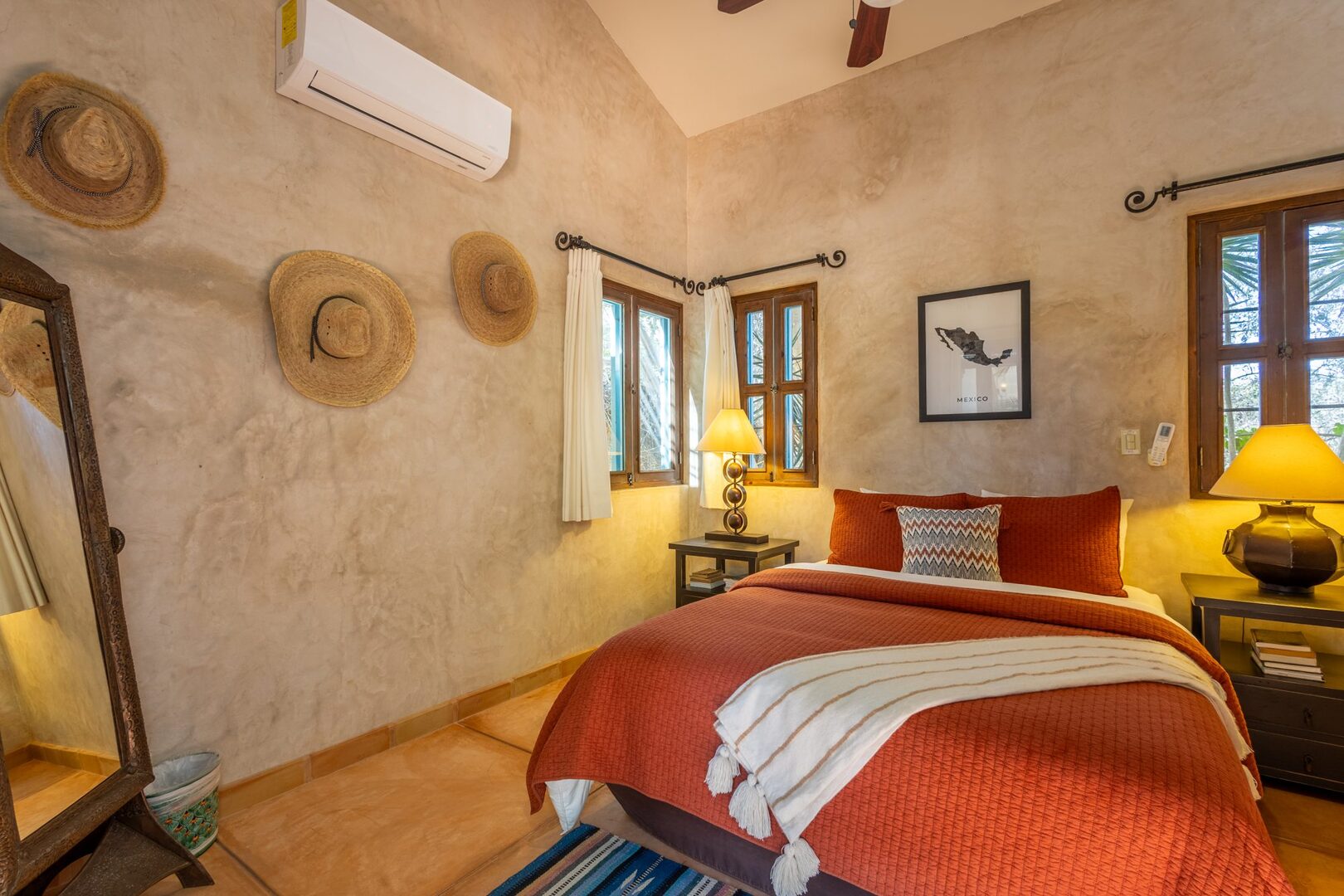 Bedroom with terracotta bedding and straw hat display