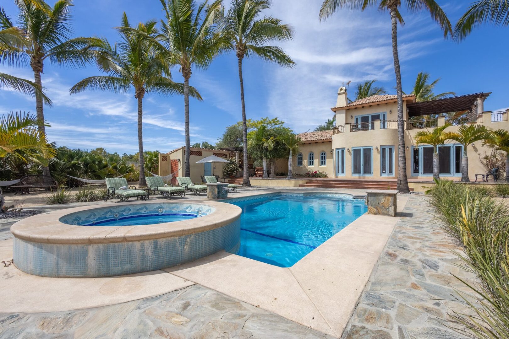 Pool and hot tub with tall palms and the main house